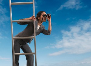 Businesswoman standing on a ladder looking through binoculars